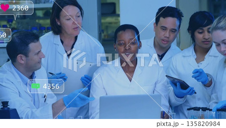Typing lab-coated blue-gloved African American scientist at lab bench, with laptop tablet clipboard Typing lab-coated blue-gloved African American scientist at lab bench, with laptop tablet clipboard 135820984
