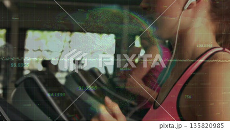 Running woman wearing pink tank top and earphones on gym treadmill with data overlay, copy space 135820985