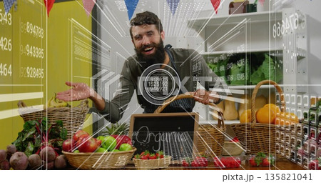 Displaying vendor wearing apron arranging baskets under bunting flags at stall, with organic sign Displaying vendor wearing apron arranging baskets under bunting flags at stall, with organic sign 135821041