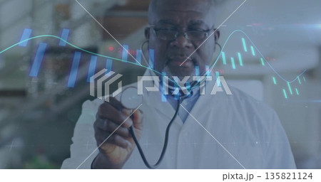 Displaying senior male doctor in white coat showing holographic charts in clinic, with stethoscope Displaying senior male doctor in white coat showing holographic charts in clinic, with stethoscope 135821124