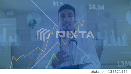 Gesturing doctor wearing lab coat, stethoscope in clinic holding clipboard with data visualizations 135821153