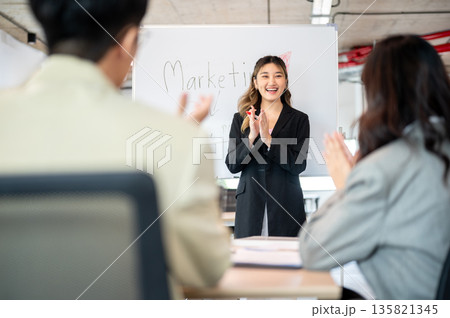 Asian businesswoman clapping hands with coworker after finished explaining marketing plan in office Asian businesswoman clapping hands with coworker after finished explaining marketing plan in office 135821345