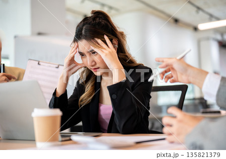 Asian businesswoman holding head getting stress or exhausted over workplace dispute at office table 135821379
