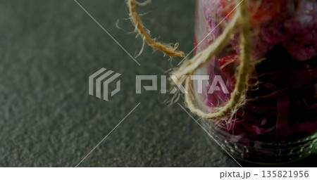 Glass jar sitting on speckled countertop in kitchen, with purple dried petals and twine, copy space Glass jar sitting on speckled countertop in kitchen, with purple dried petals and twine, copy space 135821956
