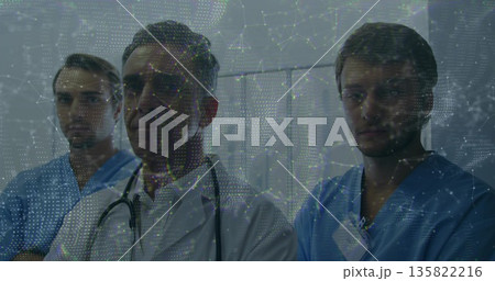 Standing staff wearing white coat and stethoscope, blue scrubs and ID badges in ward, data overlay Standing staff wearing white coat and stethoscope, blue scrubs and ID badges in ward, data overlay 135822216