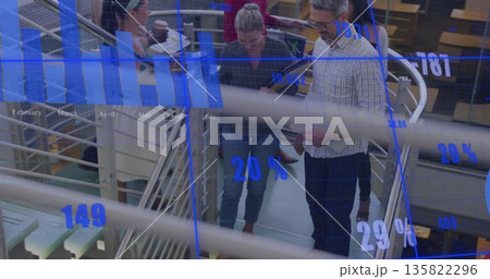 Team descending metal railing in office holding devices, coffee cup and document under data overlay Team descending metal railing in office holding devices, coffee cup and document under data overlay 135822296