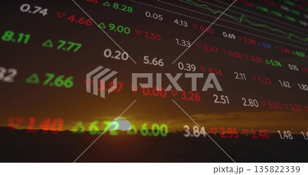 Floating financial data oscillating above sinking sun over tree line, with green and red arrows 135822339