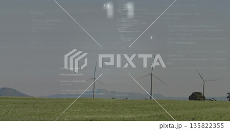 Towering three white wind turbines turning over green field at rural wind farm, with distant hills Towering three white wind turbines turning over green field at rural wind farm, with distant hills 135822355