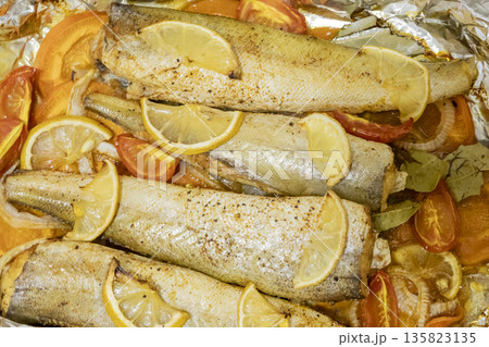 Spiced hake baked in the oven with lemon, tomatoes, carrots, and onions in foil. Delicious fish for lunch or dinner, perfect for a diet. Tasty hake fish baked with vegetables. Spiced hake baked in the oven with lemon, tomatoes, carrots, and onions in foil. Delicious fish for lunch or dinner, perfect for a diet. Tasty hake fish baked with vegetables. 135823135