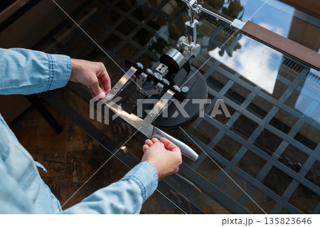 Man placing blade in knife sharpener fillet clamp. Manual sharpening device for kitchen or hunting knife maintenance. Precision angle control tool. 135823646