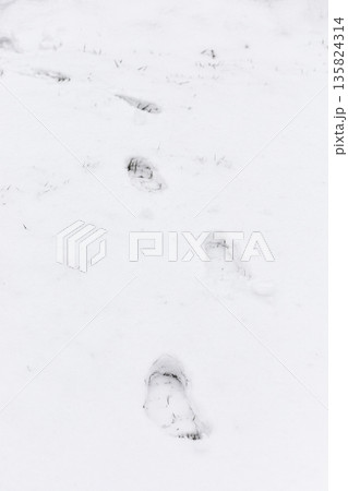 Footsteps are visible in the snow, creating a path across a winter scene. The white ground shows the impact of movement in a cold setting 135824314