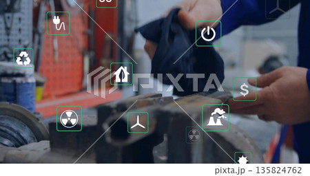 Technician wearing coveralls wiping workpiece in workshop, vise, tools and energy icons, copy space Technician wearing coveralls wiping workpiece in workshop, vise, tools and energy icons, copy space 135824762