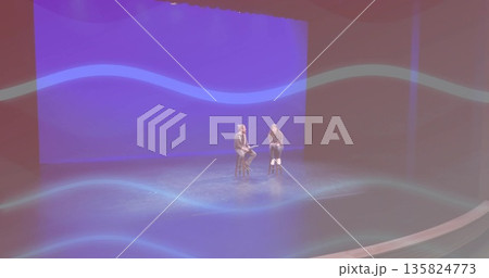 Presenter and guest holding discussion on stools under spotlight on stage with tablet blue backdrop 135824773