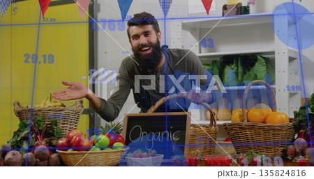 Displaying bearded vendor arranging organic produce at stall, with wicker baskets and chalkboard 135824816