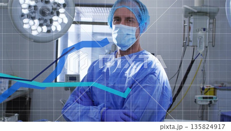 Standing mature male surgeon crossing arms in OR, with surgical light monitors data overlay 135824917