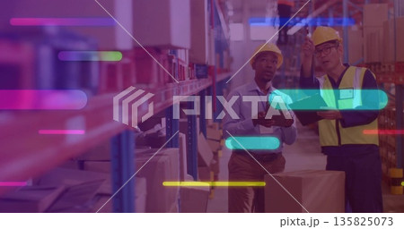 Inspecting staff in hardhats checking tablet and pointing up at racks of boxes in warehouse aisle Inspecting staff in hardhats checking tablet and pointing up at racks of boxes in warehouse aisle 135825073