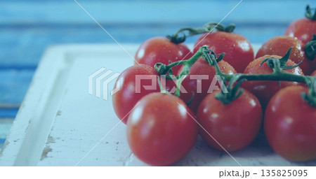 Cluster of cherry tomatoes sitting on white board at kitchen counter, with green stems and droplets Cluster of cherry tomatoes sitting on white board at kitchen counter, with green stems and droplets 135825095