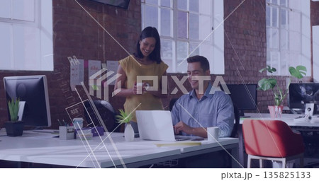 Typing male colleague using laptop at open-plan office desk, with coworker holding coffee mug Typing male colleague using laptop at open-plan office desk, with coworker holding coffee mug 135825133