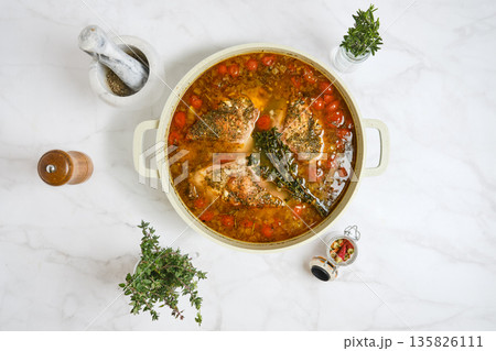 Rabbit stew with vegetables and herbs in a cooking pot on a marble surface 135826111