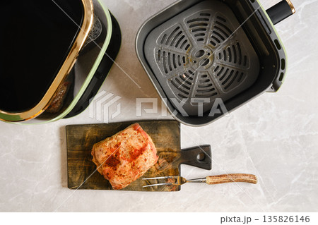 Pork tenderloin cooked in an air fryer on a wooden board in a kitchen 135826146