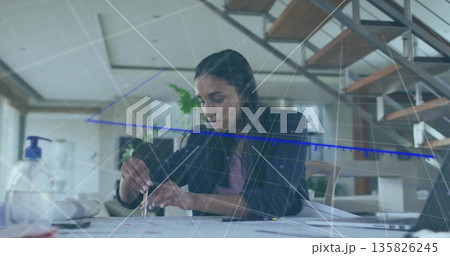 Drawing female designer sketching circle with compass at modern open-plan office desk, with plans Drawing female designer sketching circle with compass at modern open-plan office desk, with plans 135826245