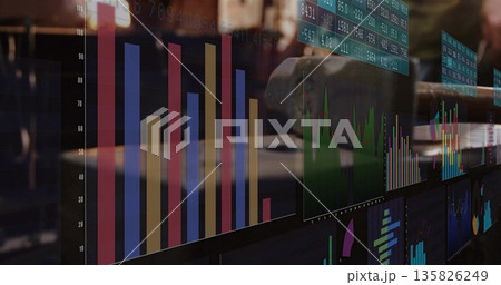 Displaying colorful bar graph with green line on computer monitors at trading desk, with keyboard Displaying colorful bar graph with green line on computer monitors at trading desk, with keyboard 135826249