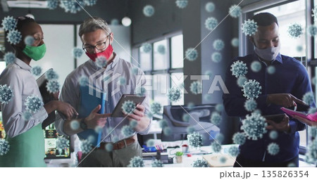 Collaborating coworkers wearing masks around desk at office, with tablets and virus overlays Collaborating coworkers wearing masks around desk at office, with tablets and virus overlays 135826354