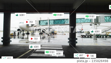 Parking commercial jet airliner connecting to green jet bridge at airport apron, with baggage carts 135826498