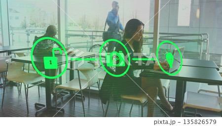 Typing woman wearing jacket on laptop in cafe with green padlock camera lightbulb icons, copy space 135826579