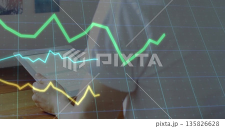 Reviewing papers man in button-up shirt at office desk, with grid and colored line graphs Reviewing papers man in button-up shirt at office desk, with grid and colored line graphs 135826628