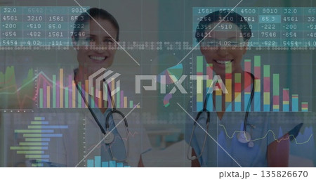 Standing two doctors wearing lab coat and scrubs examining data charts in clinic, with stethoscopes 135826670