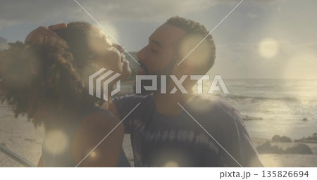 Leaning couple embracing at seaside boardwalk during sunset, metal railing casting warm glow Leaning couple embracing at seaside boardwalk during sunset, metal railing casting warm glow 135826694