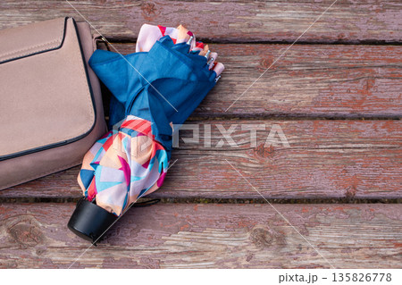 Umbrella on bench next to a woman bag with copy space. Weather change, rainy weather or forgotten item concept for autumn or spring. Umbrella on bench next to a woman bag with copy space. Weather change, rainy weather or forgotten item concept for autumn or spring. 135826778
