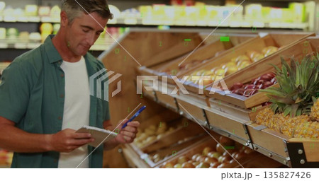 Inspecting employee wearing green shirt noting stock in produce aisle, with notebook, copy space 135827426