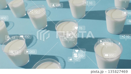 Social media icons hovering above clear plastic cups with white yogurt on blue table, with counters Social media icons hovering above clear plastic cups with white yogurt on blue table, with counters 135827469