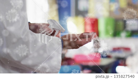 Pressing lab coat hands dispensing sanitizer in classroom, with clear spray bottle and open palm Pressing lab coat hands dispensing sanitizer in classroom, with clear spray bottle and open palm 135827540