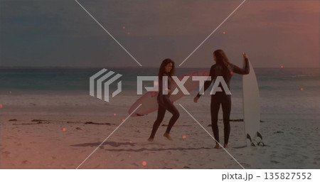 Holding pink and white surfboards, couple facing each other on sandy beach, full-length wetsuits Holding pink and white surfboards, couple facing each other on sandy beach, full-length wetsuits 135827552