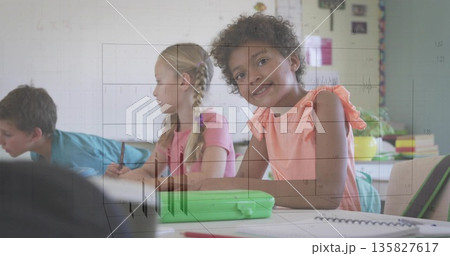 Smiling student in orange sleeveless top sitting at desk in school classroom, with notebooks 135827617