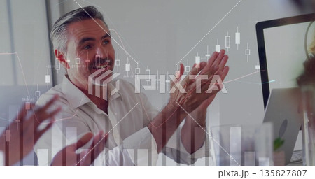 Clapping executive in white shirt watching monitor in virtual meeting room, with chart overlays Clapping executive in white shirt watching monitor in virtual meeting room, with chart overlays 135827807