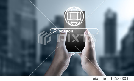 Hands holding a mobile phone with a digital search bar and globe icon against a blurred urban background. Concept of global information technology, connectivity, and internet search Hands holding a mobile phone with a digital search bar and globe icon against a blurred urban background. Concept of global information technology, connectivity, and internet search 135828032