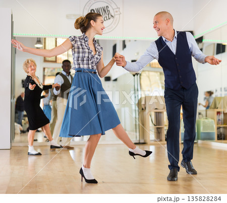Adult dancing couple enjoying active swing Adult dancing couple enjoying active swing 135828284