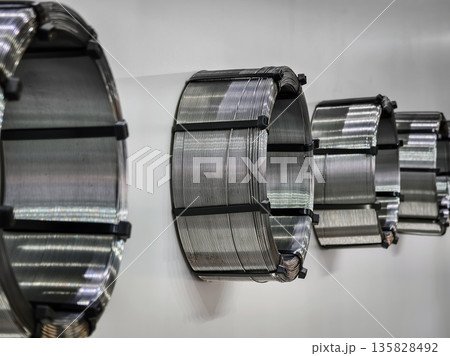 Coils of metal wire arranged on wall in workshop for manufacturing purposes 135828492