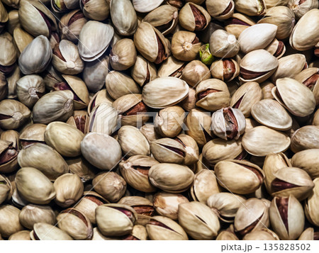Pistachio nuts in a close-up view showing their shells and kernels on a light background Pistachio nuts in a close-up view showing their shells and kernels on a light background 135828502