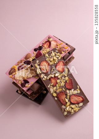 Chocolate bar with freeze-dried berries and nuts on pastel background 135828558