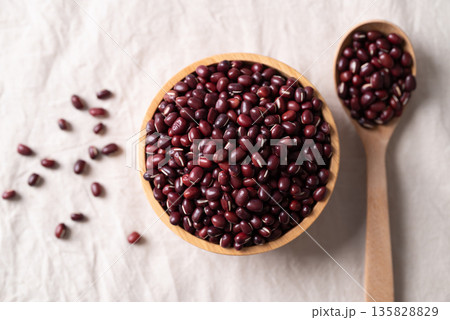 Azuki beans, Adzuki bean or red mung beans in wooden bowl and spoon on white fabric background, Azuki beans, Adzuki bean or red mung beans in wooden bowl and spoon on white fabric background, 135828829