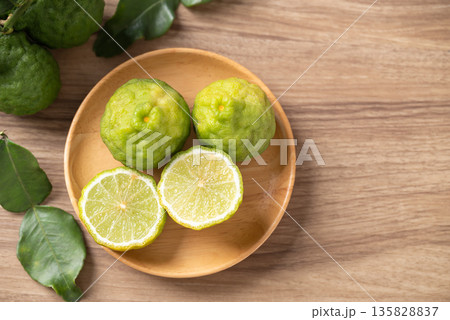 Kaffir lime fruit with leaf on wooden background, Thai food ingredient, Table top view 135828837