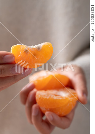 Peeled Mandarin orange fruit holding by hand and eating Peeled Mandarin orange fruit holding by hand and eating 135828851