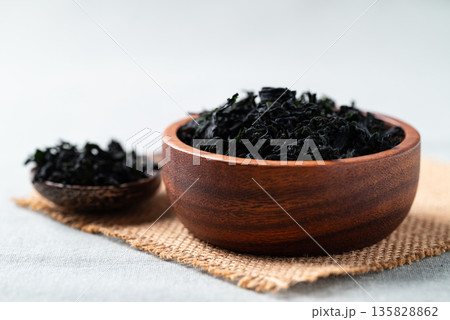 Dried wakame seaweed in a wooden bowl and spoon, Healthy Asian food ingredient Dried wakame seaweed in a wooden bowl and spoon, Healthy Asian food ingredient 135828862