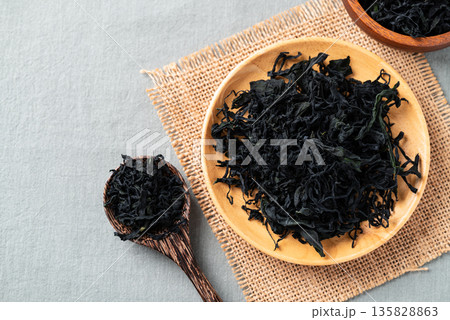 Top view of dried wakame seaweed on a wooden plate and spoon, Healthy Asian food ingredient Top view of dried wakame seaweed on a wooden plate and spoon, Healthy Asian food ingredient 135828863