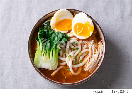 Top view of spicy Udon Noodle Soup topped with Bok Choy, Enoki Mushrooms and Soft Boiled Egg 135828867